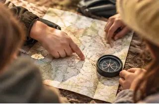 Niños resolviendo pruebas de orientación con mapas y brújulas durante una gymkana escolar